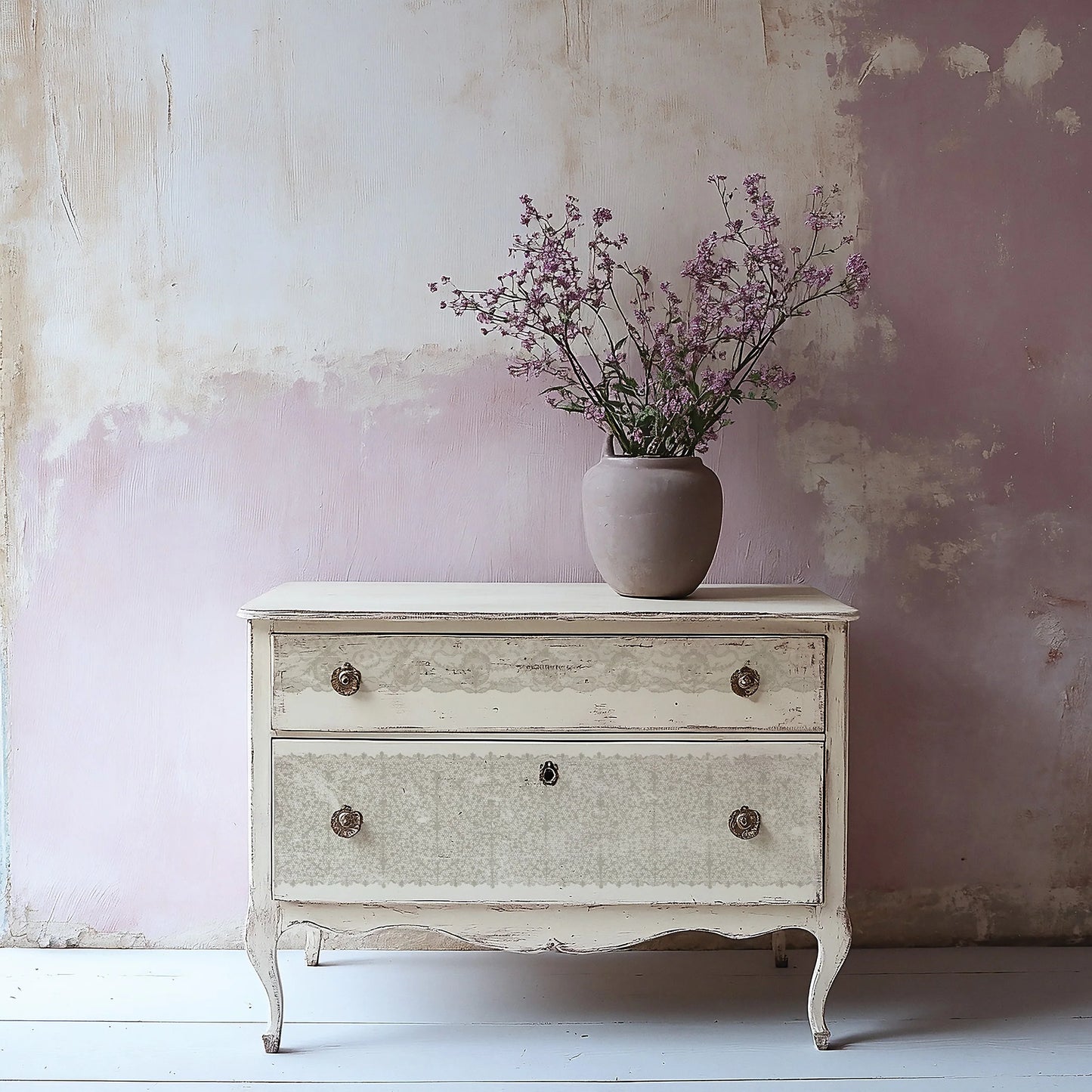 A stamped lace design on a vintage-style dresser with a vase of flowers against a textured wall.