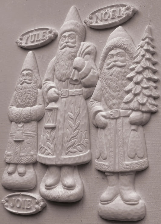 Three clay-cast Santa Claus figures in a relief style, labeled Yule, Noel, and Joy, on a textured gray background.