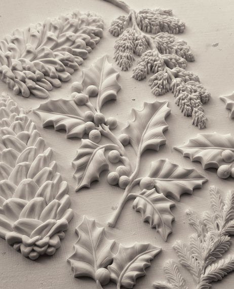 Decorative clay castings with holly, pine cone, and pine needle patterns made from IOD's "Winter Forage" mold