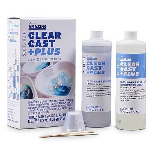 A product image showing a Clear Cast Plus Epoxy Resin Kit by Alumilite. The image includes two bottles of resin, measuring cups, and wooden sticks for mixing, all displayed with the packaging box in the background.