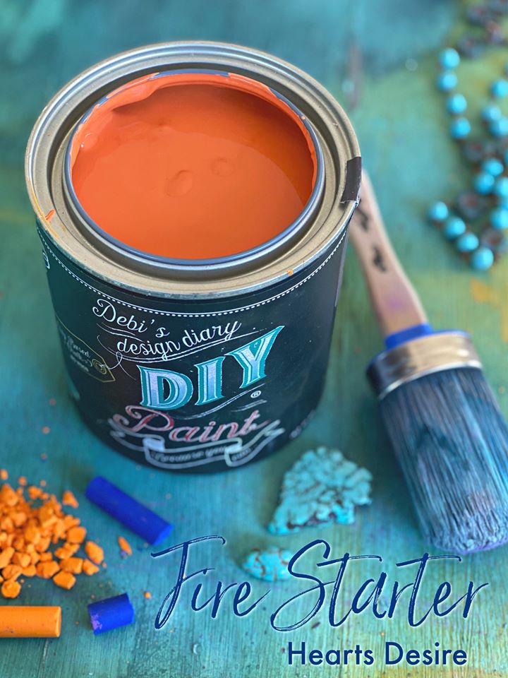 Open can of orange chalk paint with brush on the side