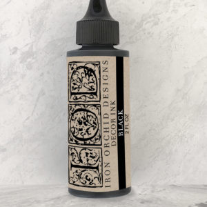 A bottle of Iron Orchid Designs ink in black color, with a label featuring floral patterns.