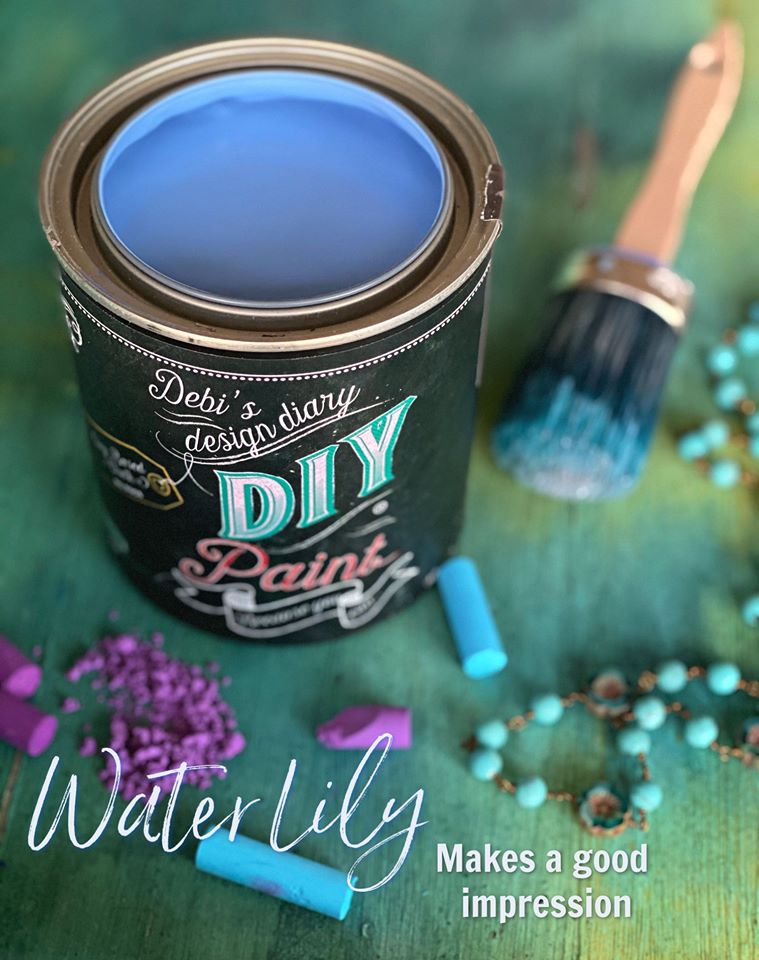 A can of Water Lily DIY paint in blue color with a brush and some pearls on a green surface.