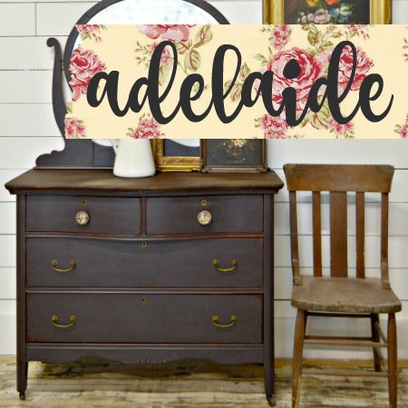 An antique wooden dresser and chair with a sample of dark plum colored 'Adelaide' milk paint from Sweet Pickins, displayed on top of the dresser.