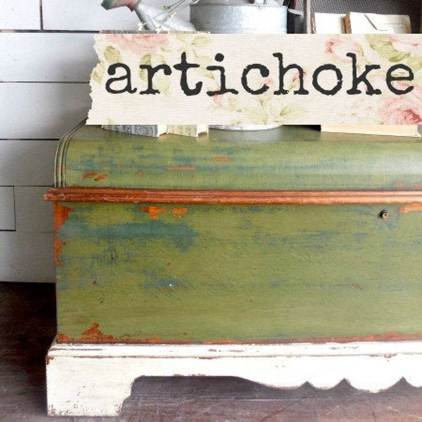 A sample of 'Artichoke' milk paint by Sweet Pickins, displayed on a piece of furniture, with the brand name and color description on a rustic sign.