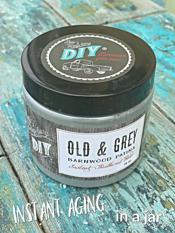A jar labeled 'Old & Grey Liquid Patina' with text indicating it's for instant aging in a jar, placed on a wooden surface.