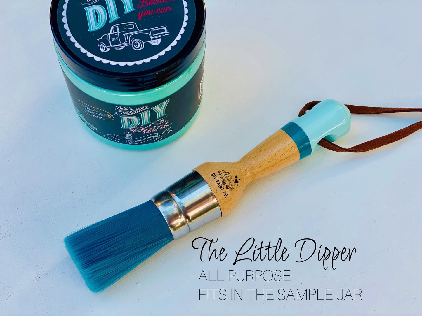 A brush called the Little Dipper, lying sideways on a table next to a jar of DIY Paint co. paint.