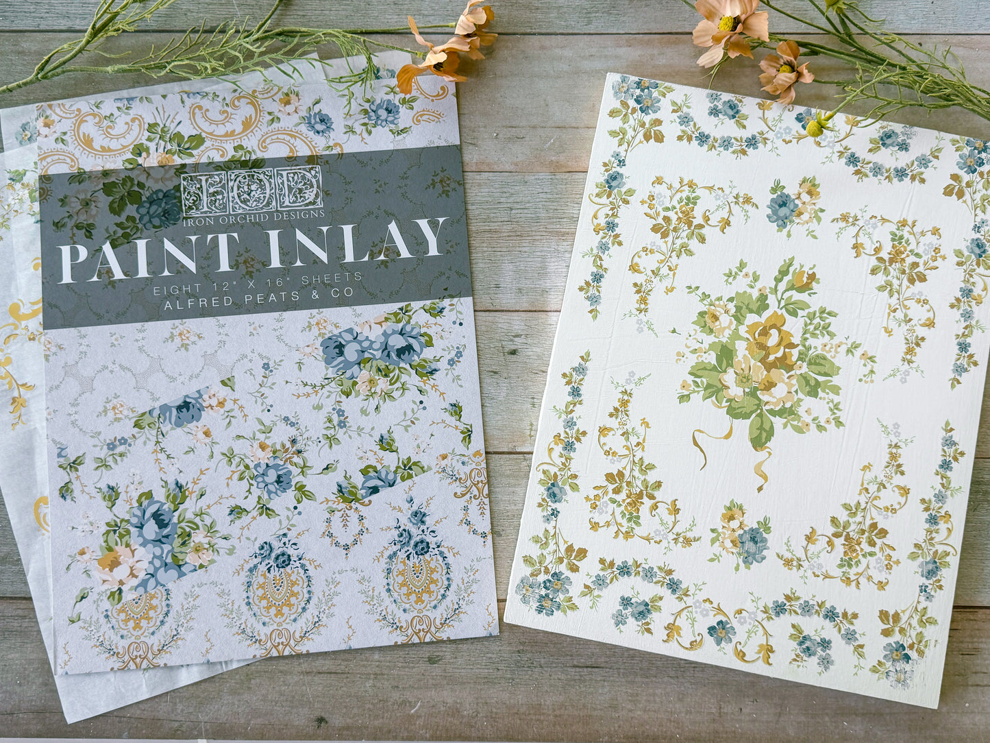 Floral patterned paper with 'Paint Inlay' packaging on a wooden surface