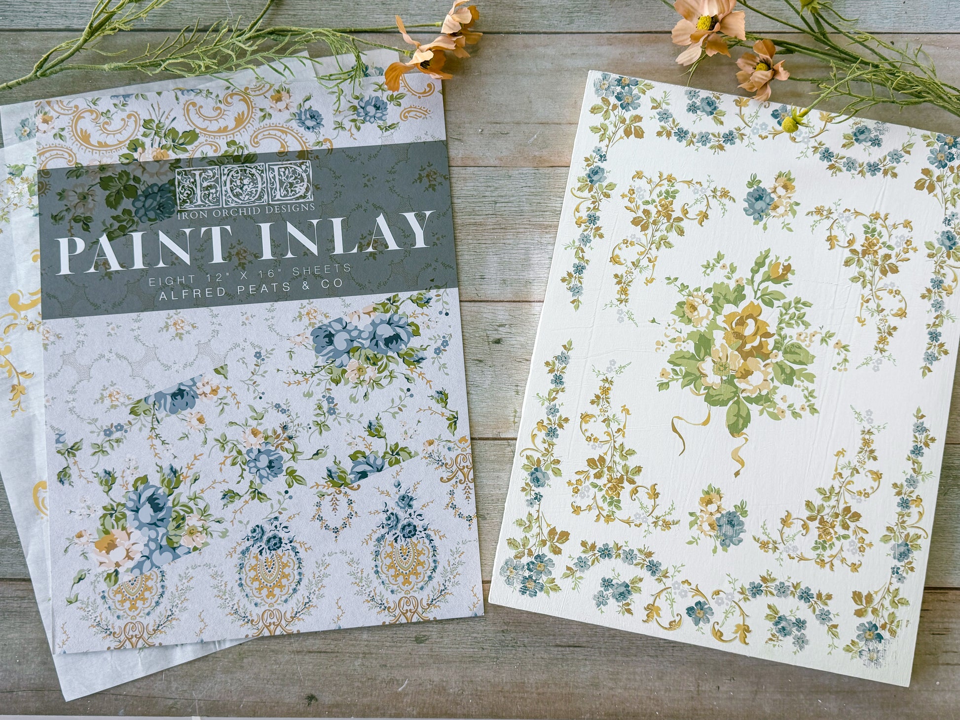 Floral patterned paper with 'Paint Inlay' packaging on a wooden surface