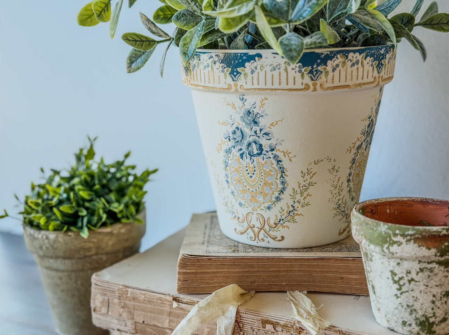 Decorative pot with floral patterns on a stack of books against a light blue background