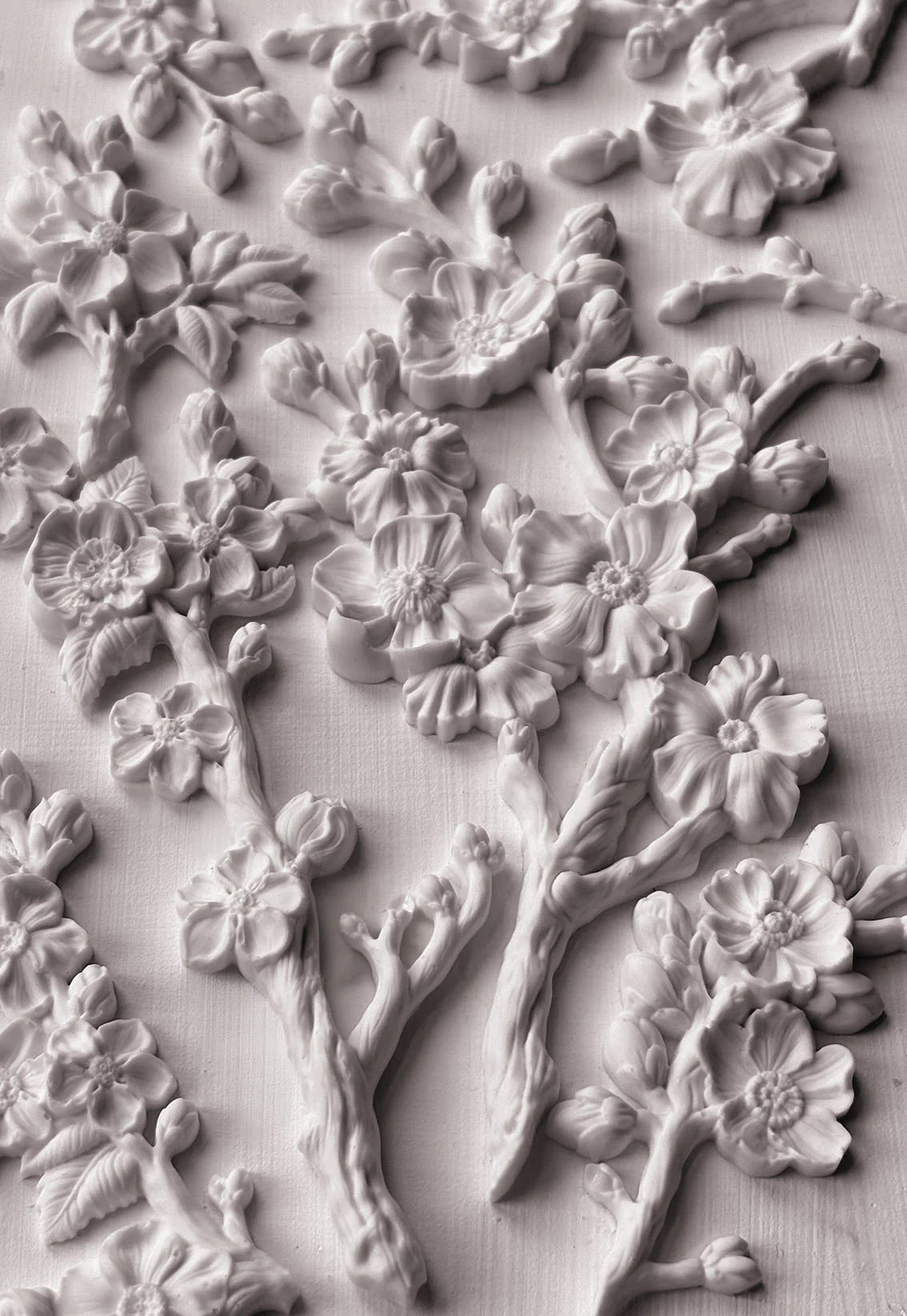 Clay cast cherry blossoms on wood.