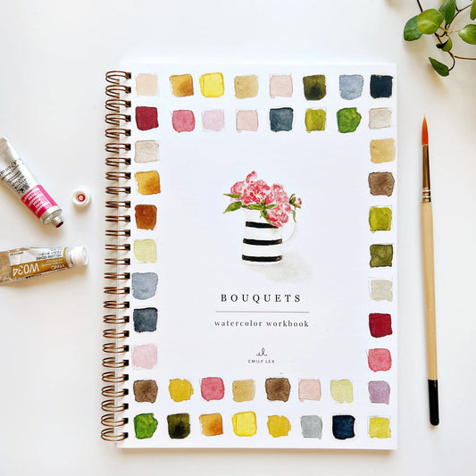Front cover of a watercolor workbook titled 'Bouquets' with a floral illustration on the cover, placed on a white surface accompanied by some art supplies.