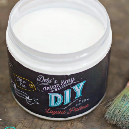 Open 16 oz. Plastic jar of DIY Paint Co.’s Clear liquid patina with a brush beside it.