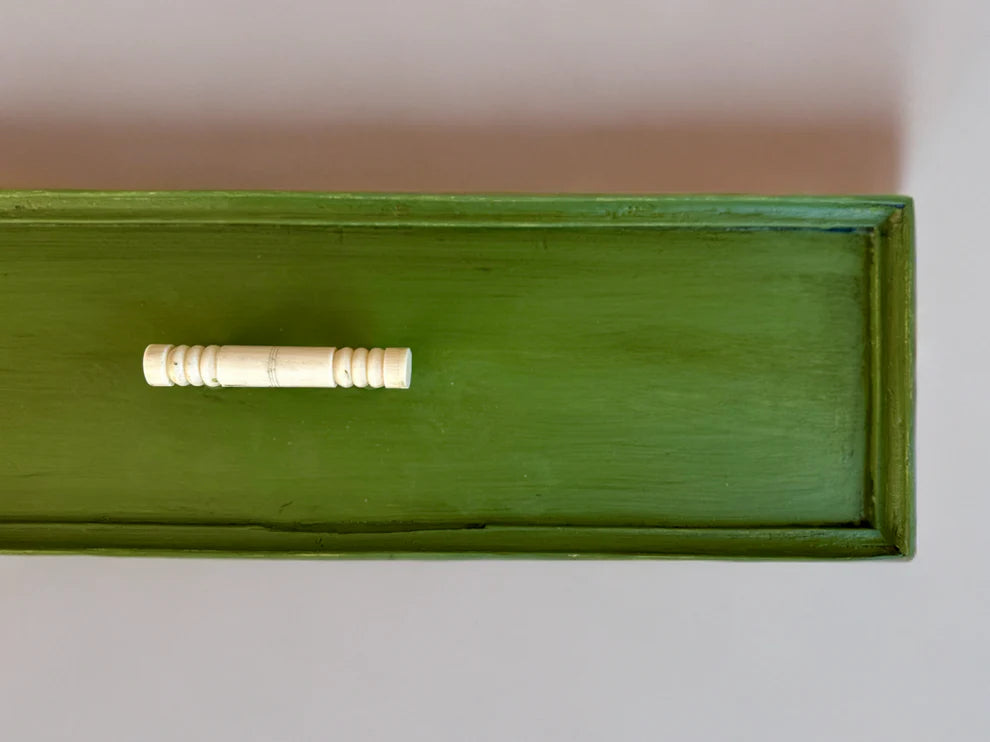 A drawer painted in the green color "Garden Sage" with a white backdrop and white handle on drawer.
