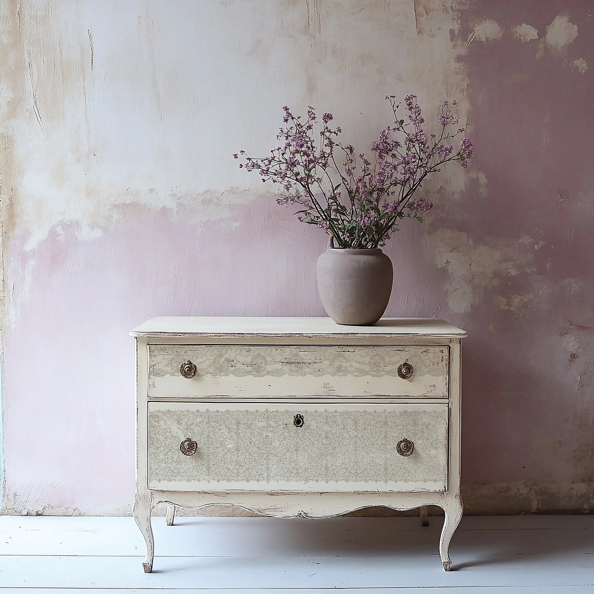 A stamped lace design on a vintage-style dresser with a vase of flowers against a textured wall.