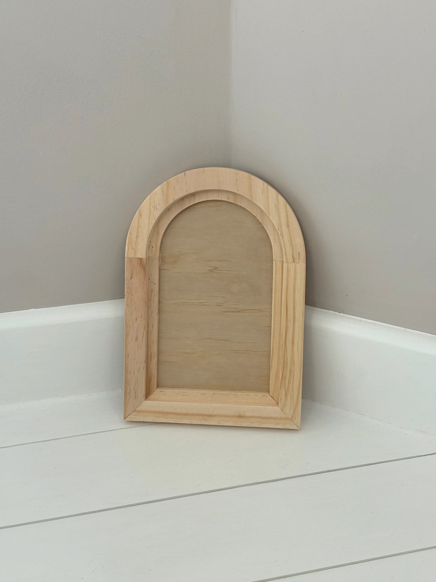 Wooden arch-shaped gallery blank on a white surface with a gray wall background