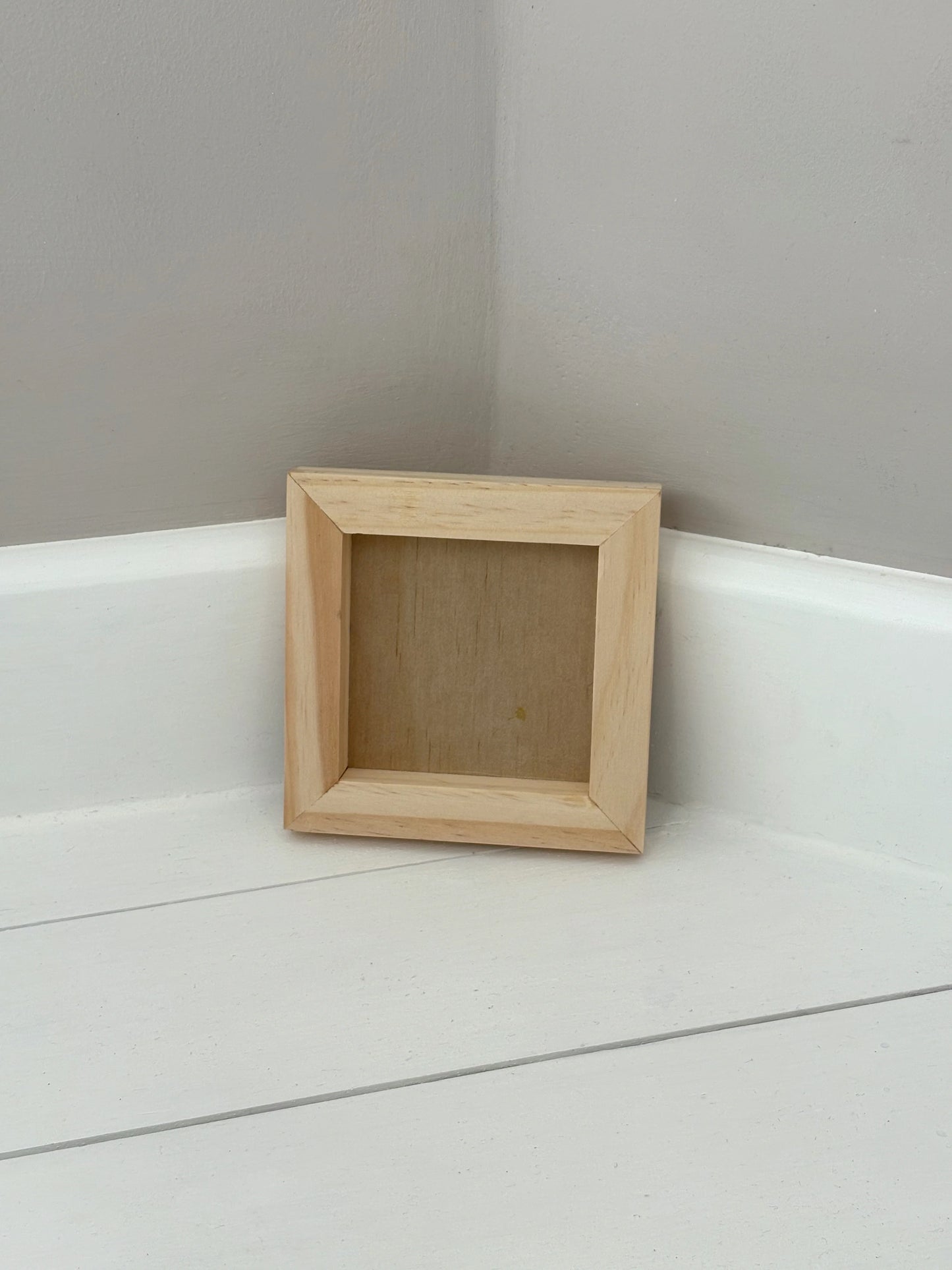 Wooden 5 inch by 5 inch gallery blank on a white surface with a gray wall background