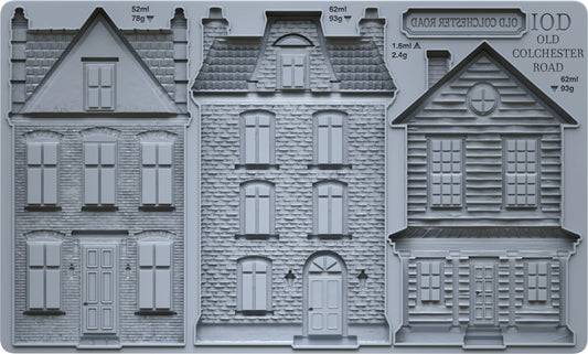 Three gray miniature house moulds or relief designs shown side by side, with printed text reading 'IOD OLD COLCHESTER ROAD' and small measurements above each building.