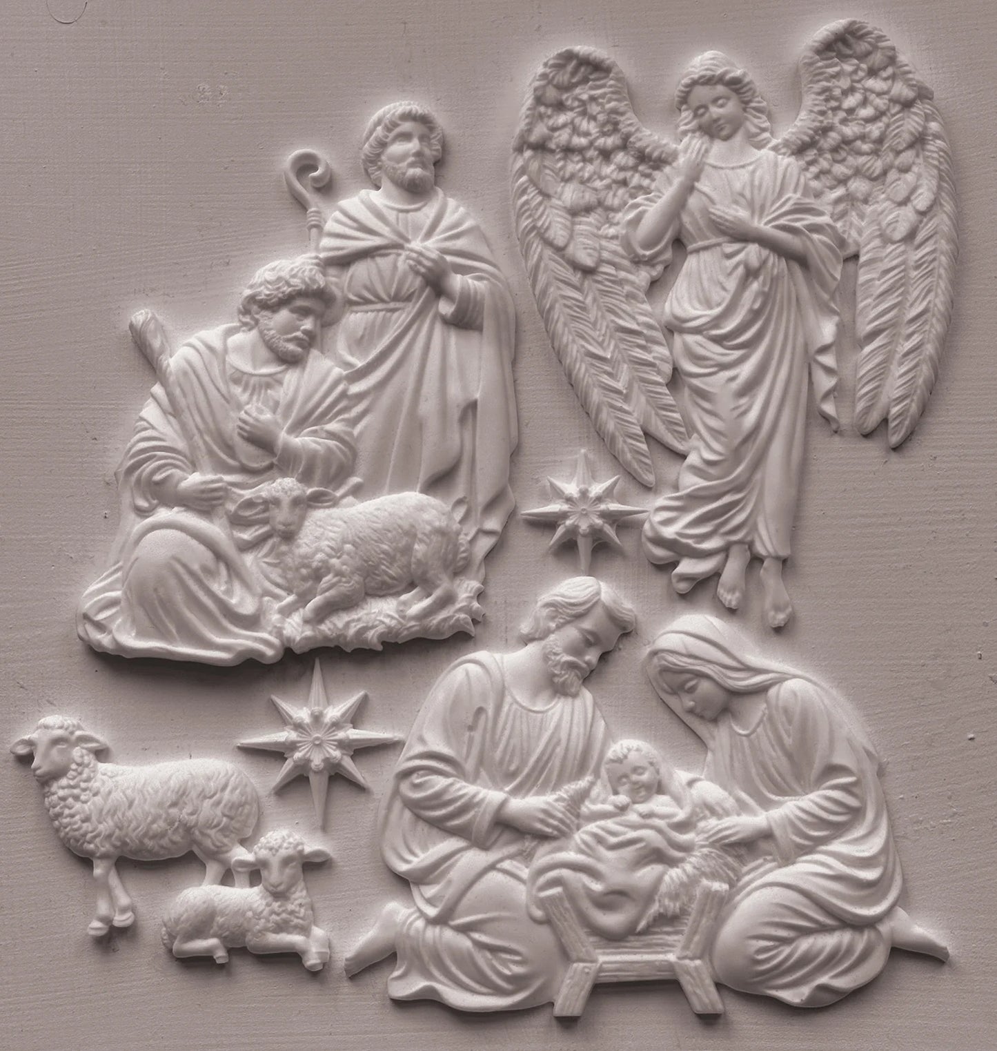 White resin castings featuring a nativity scene with Mary, Joseph, baby Jesus, angels, and sheep, shown against a matching light gray textured background.