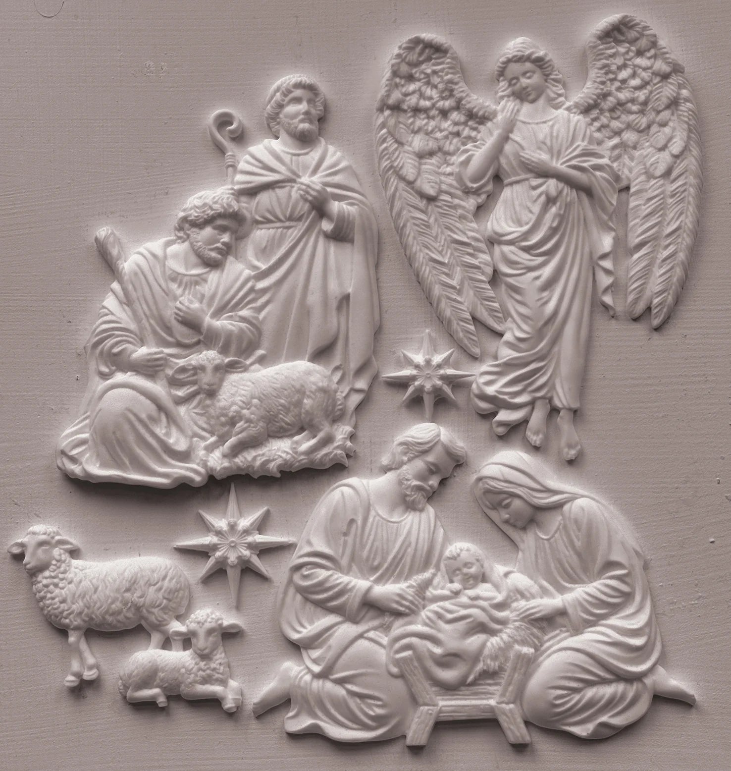 White resin castings featuring a nativity scene with Mary, Joseph, baby Jesus, angels, and sheep, shown against a matching light gray textured background.