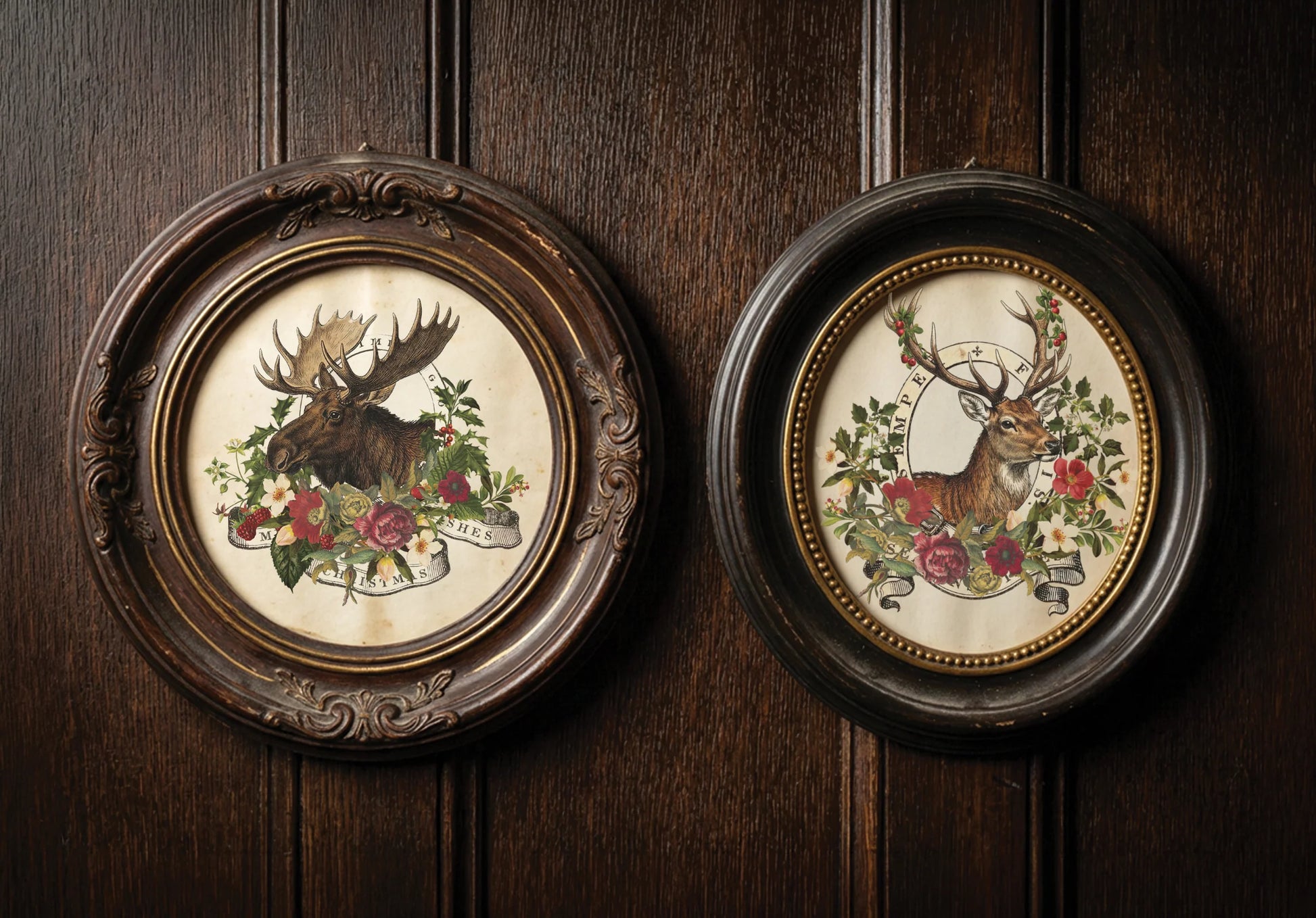 Two round framed wall art pieces hanging on a dark wood paneled wall. The left frame shows a moose surrounded by flowers, and the right frame shows a deer surrounded by flowers, both in ornate dark wood frames.