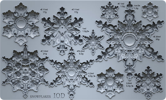 A gray silicone mold tray featuring multiple ornate snowflake designs of varying sizes, each labeled with its volume in milliliters and weight in grams. The bottom left corner displays the text 'SNOWFLAKES IOD'.