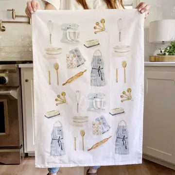 Person holding a kitchen-themed towel with various utensils and appliances in a kitchen setting.