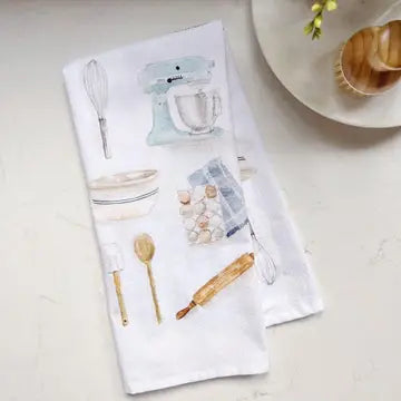 Kitchen-themed towel with illustrations of baking tools on a light surface.
