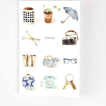 A notebook with a softtouch cover featuring watercolor illustrations of everyday items such as a camera, umbrella, and notebook.