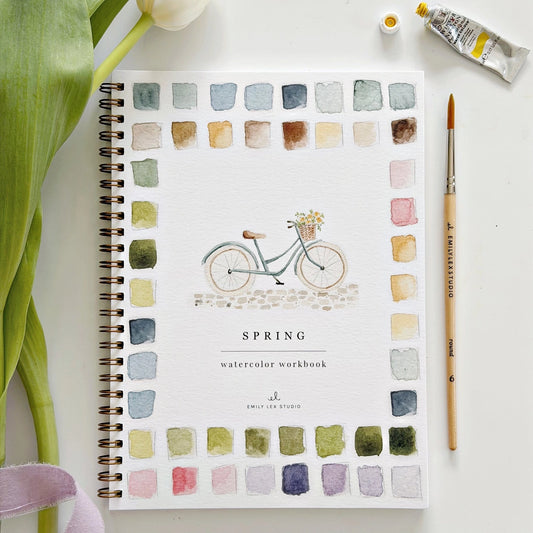 Spring watercolor workbook with a bicycle illustration and color swatches on a white surface.