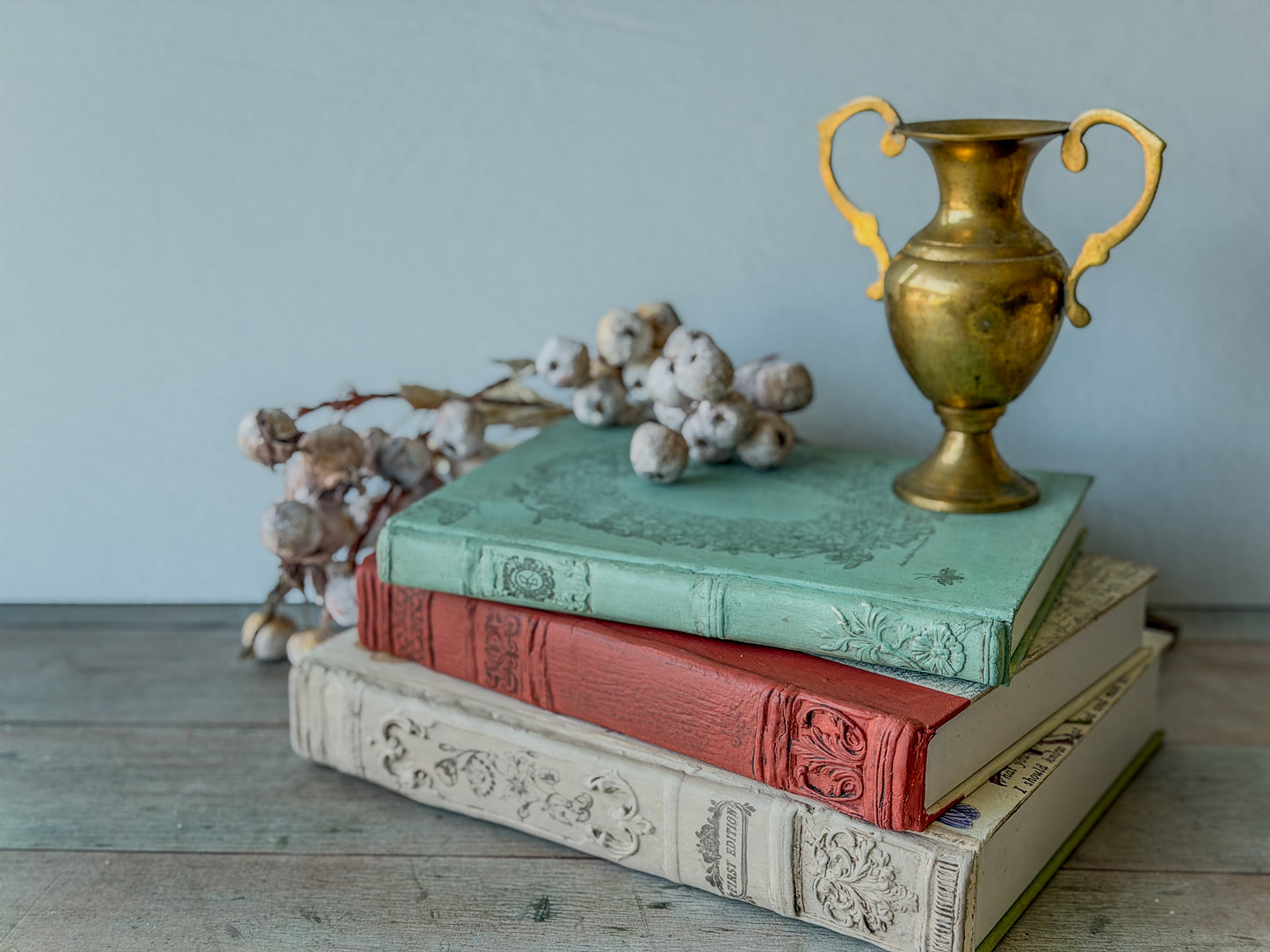 Three stacked decorative books, each spine made with the Bookish mould and painted and stamped.