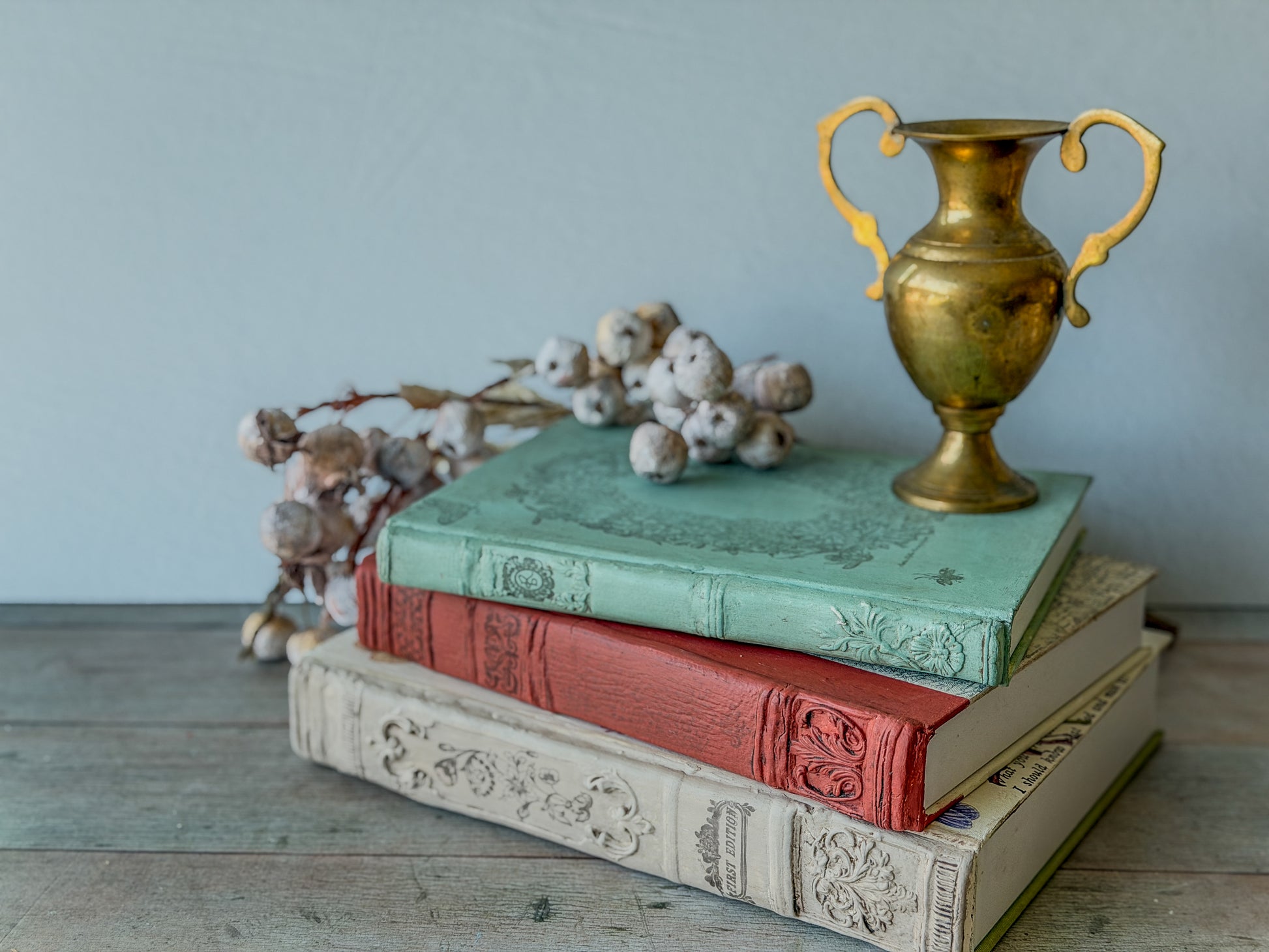 Three stacked decorative books, each spine made with the Bookish mould and painted and stamped.