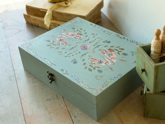 Decorative wooden box with floral patterns on a wooden surface