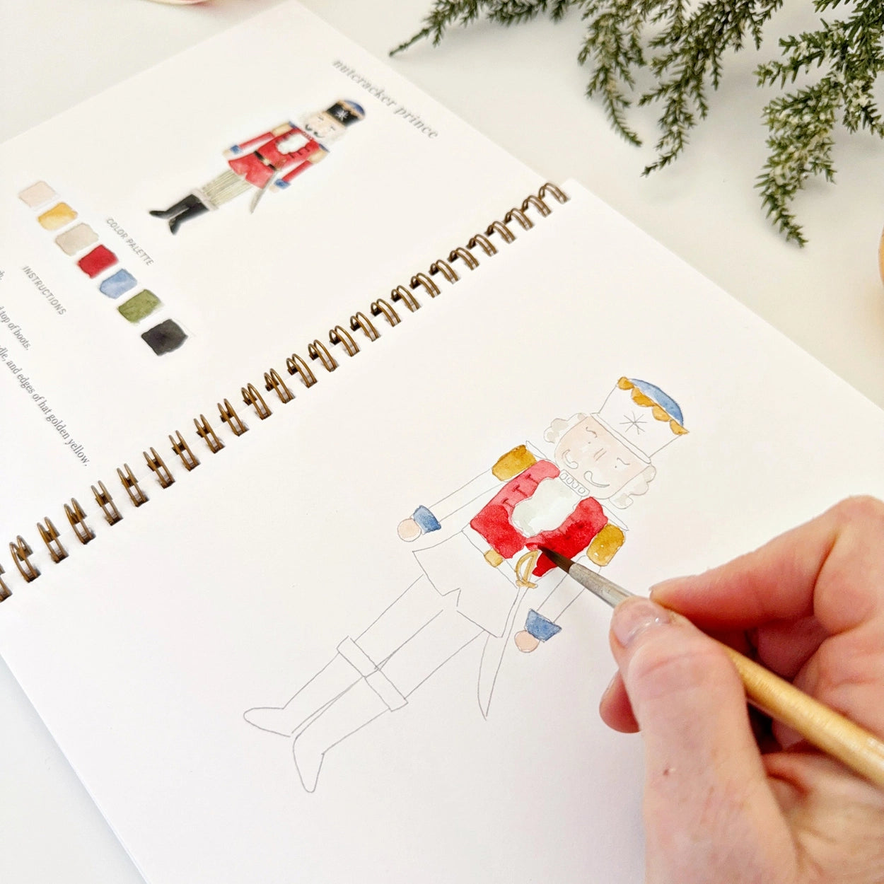 A person following watercolor instructions for painting nutcracker soldier