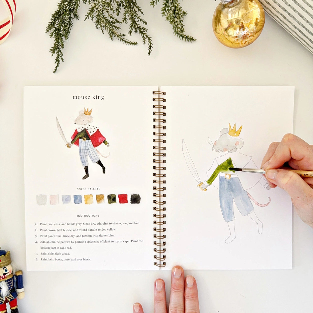 Step-by-step watercolor instructions for painting a mouse king, with a human hand actively painting.