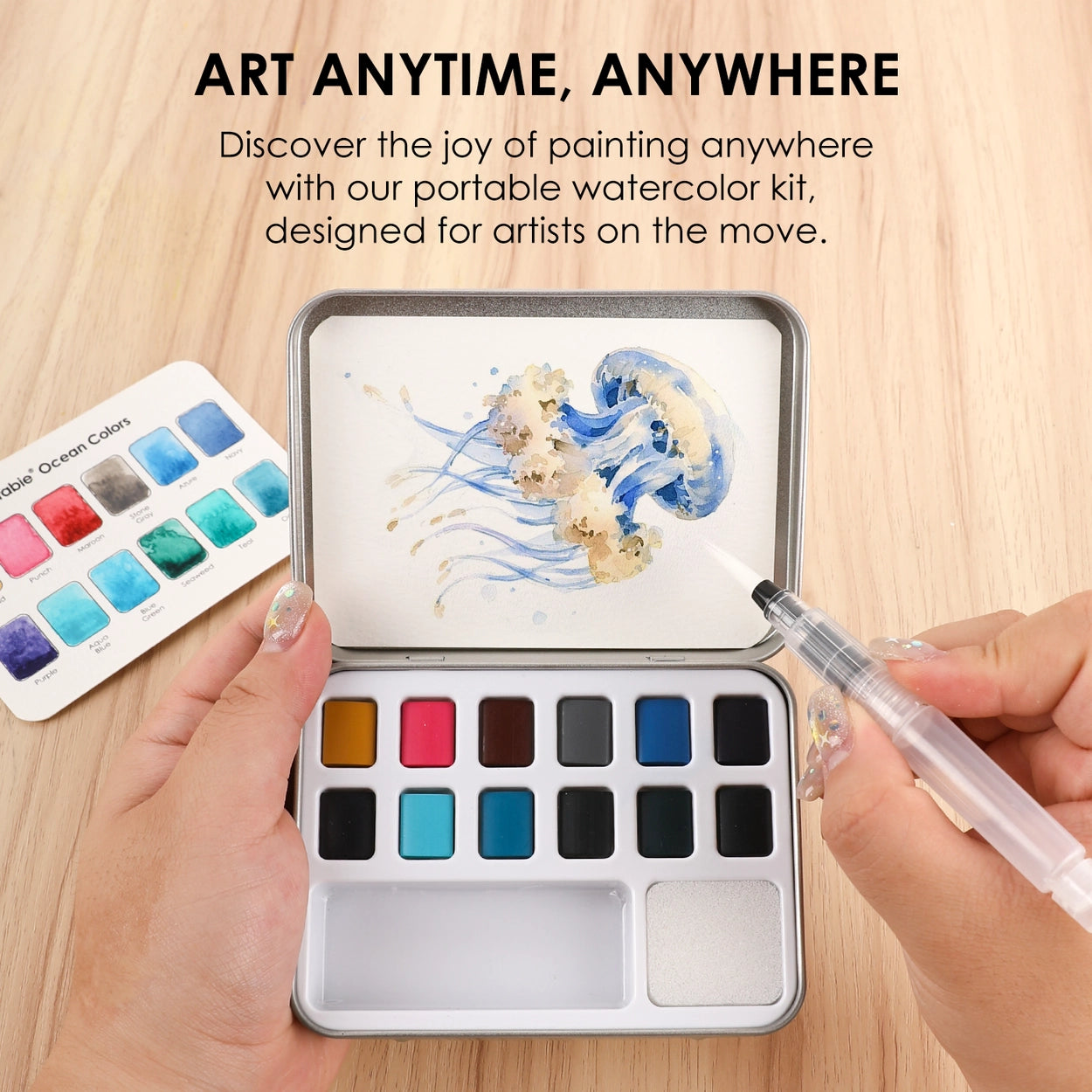 Portable watercolor kit with paint swatches and a pen on a wooden surface, with text 'Art Anytime, Anywhere'.