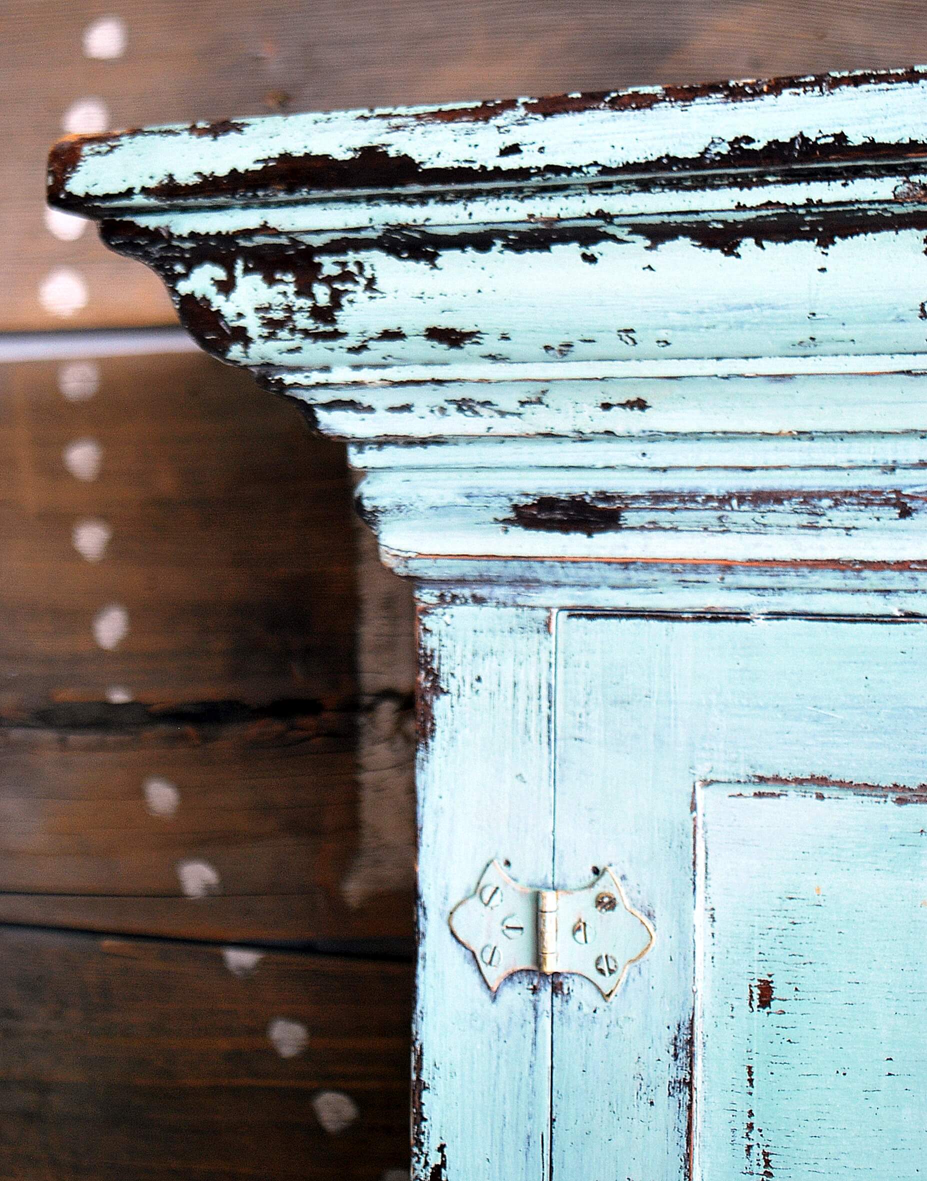 The corner of a cabinet painted with milk paint in the shade "Sweetie Jane", with distress marks added for artistic effect.