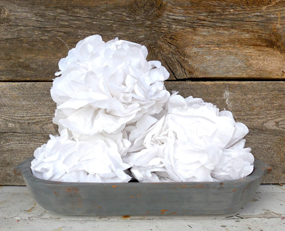 White flowers in a grey milk-painted wood bowl up against a wooden background
