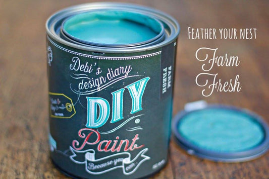 A can of 'DIY Paint' labeled 'Farm Fresh' with a sample jar shown in front, on a wooden surface.