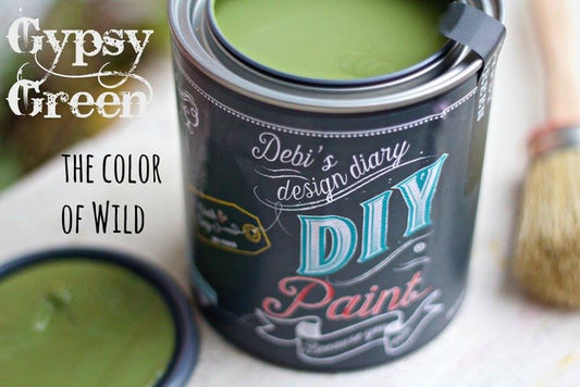An open can of DIY Paint in the color Gypsy Green, with a sample jar labeled 'GYPSY GREEN' and a brush beside it.
