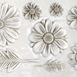 A decorative mold featuring floral designs, with prominent flowers and leaves in a white color.