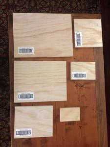 A collection of wooden art gallery panels of various sizes placed on a table, with barcodes visible on them.