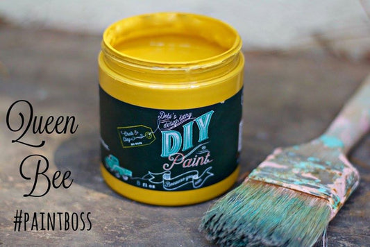 A yellow jar of Queen Bee DIY paint with a brush in the foreground, indicating the paint is for crafting or DIY projects.