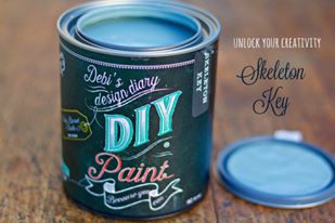 An open can of gray paint called Skeleton Key, with a colorful label, indicating Debi's DIY design as the maker.