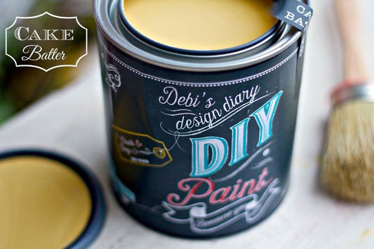 An open can of DIY Paint brand cake batter paint with a brush in the foreground.